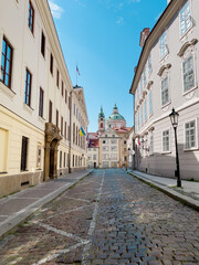 Fototapeta na wymiar Narrow Alley in Prague with St. Nicholas Church in the background