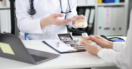 Doctor show patient in clinic silicone implants for enlargement closeup. Cosmetic surgery concept