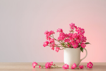 pink roses in ceramic vase on pink background