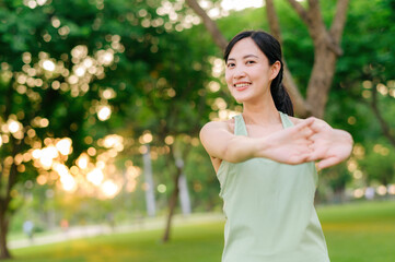 Female jogger. Fit young Asian woman with green sportswear stretching muscle in park before running and enjoying a healthy outdoor. Fitness runner girl in public park. Wellness being concept