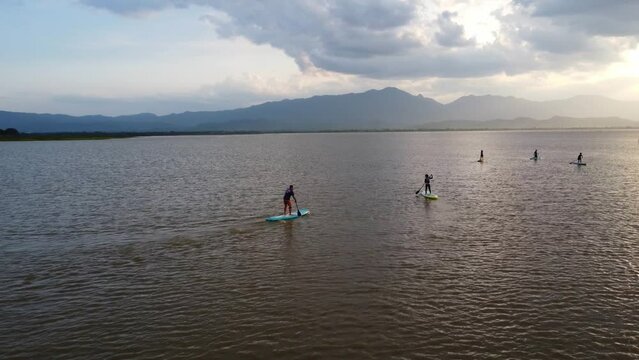 Experience the serene beauty of people paddling boarding on a tranquil lake. Embrace the active lifestyle, explore nature, joy and relaxation. Phayao Lake, Thailand.