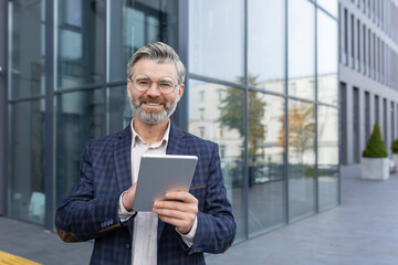 Portrait of a mature successful businessman boss, business owner smiling and looking at the camera,...