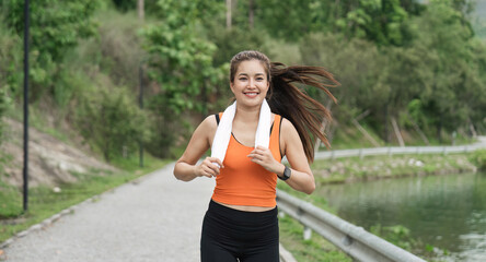 Jogging woman running in park on beautiful day off. Sport fitness model of asian ethnicity training outdoor for marathon
