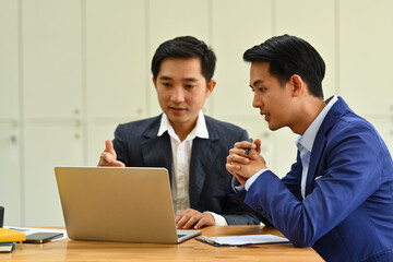 Obraz premium Shot of two startup businessman using laptop and discussing company financial project together