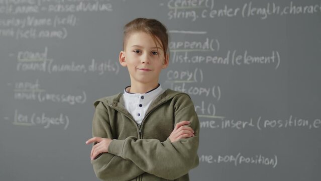 Slowmo portrait of elementary school Caucasian boy standing in front of blackboard in classroom during programming lesson at daytime
