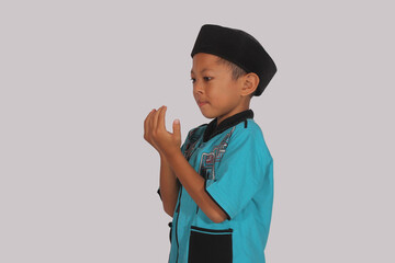 Asian cleft lip boy focused on praying with raised hands
