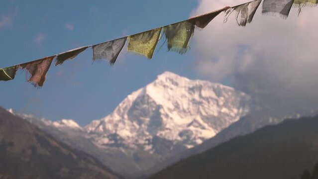 close up of Nepali prayer flags in first plane and a big snowy mountain in the background - Nepal