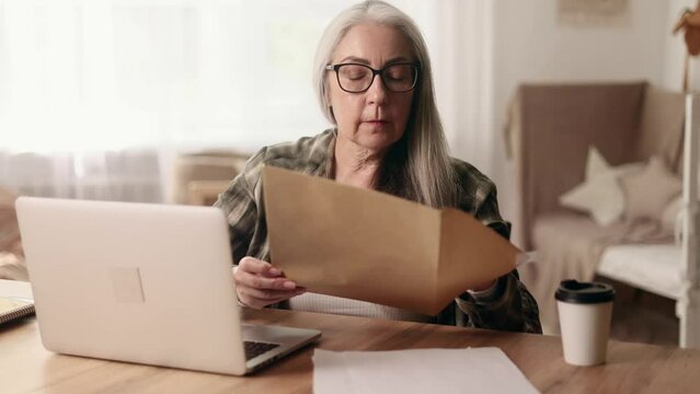 Senior woman with glasses checking mail open envelope and celebrate win success reading great news feel amazed happy reading message mail at home Triumph Lucky Wow concept