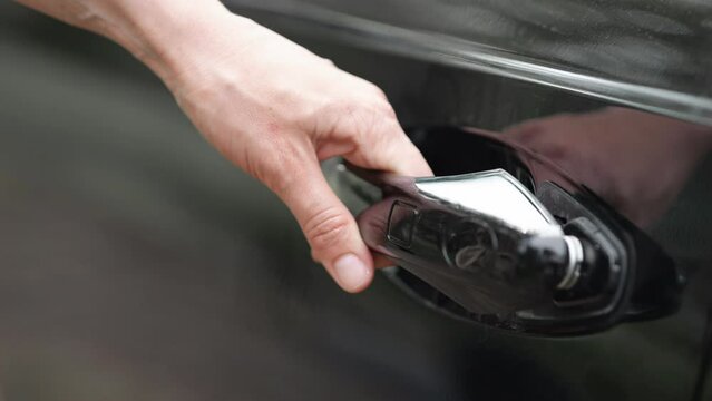 Automobile owner pressing small button to open modern car on road. Female driver struggles to open car jerking at vehicle doorknob closeup