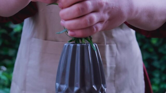 A woman in a red dress puts a bouquet of lavender in a vase. slow motion. close up