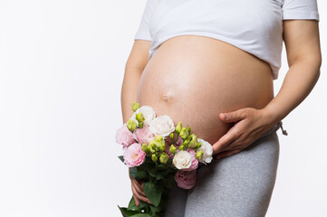 Beauty close-up portrait of gravid expectant mother holding bouquet of flowers near her pregnant belly, gently caressing her abdomen, isolated white background. Women's health and gynecology concept