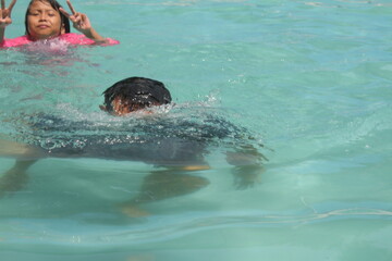 boys and girls practice swimming and playing in water
