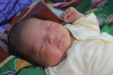 Portrait of a newborn boy who sleeps sweetly and smiles in he sleep in red clothes at a photo shoot of newborns

