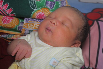 Portrait of a newborn boy who sleeps sweetly and smiles in he sleep in red clothes at a photo shoot of newborns

