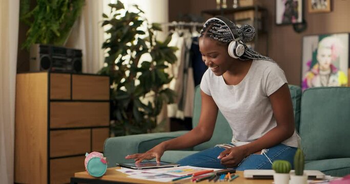 With a pair of headphones adorning her ears, the woman immerses herself in the world of music as she draws. The rhythmic melodies fuel inspiration, allowing translate the beats into fashion sketches.