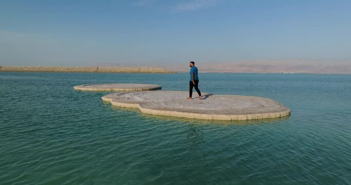 Man Walks On Large Slab Of Solid Salt In The Dead Sea In Israel. drone ascend