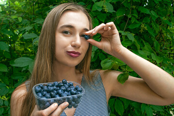 Portrait of smiling woman with blueberry. Benefits of blueberries to improve vision