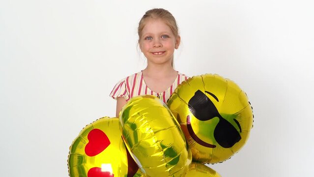 Super cool school girl with emoji balloons. Girl in a striped dress. Congratulations on your return to school. Festive mood concept. Portrait of a young beautiful smiling girl with golden balloons