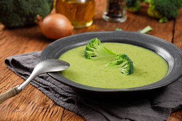 Broccoli cream soup in a black plate on a wooden background