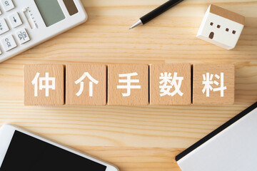 仲介手数料と書かれたブロック、電卓、スマホ、ミニチュアの家