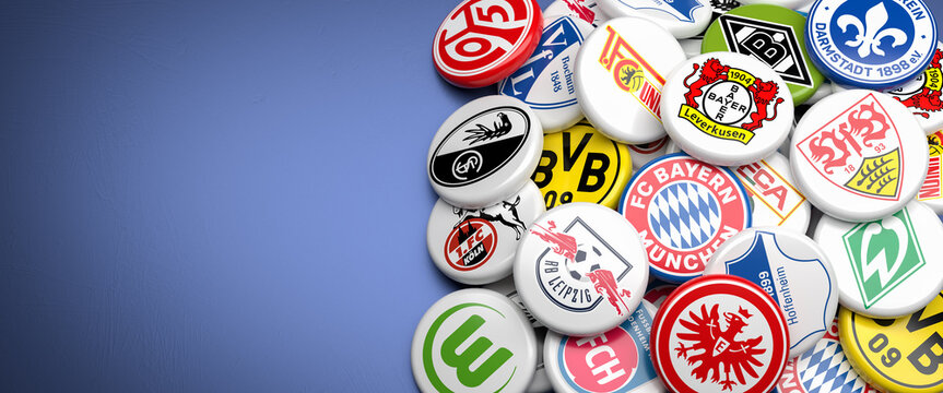 Logos of the German Soccer Clubs competing in the Bundesliga season 23/24 on a heap on a table. Copy space. Web banner format