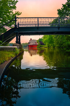 Bridge over the river at sunrise with the view of red wall boathouse and water reflections 