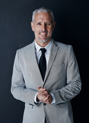 Studio portrait of senior businessman in suit, smile and handsome face on dark background....