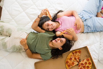 Relaxed teen girls relaxing while eating pizza together