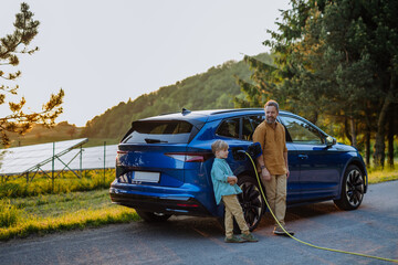 Father and his son charging electric car during their trip.