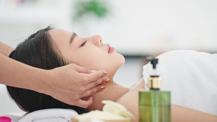 Obraz na płótnie Canvas Close up face of beautiful asian woman lying on spa bed relaxing with facial massage treatment. Masseuse massage on woman face. Beauty treatment concept