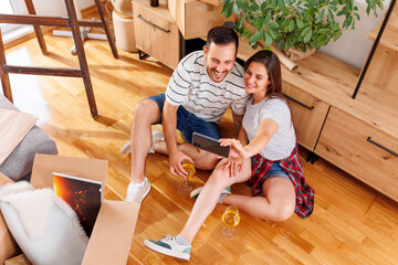 Fototapeta na wymiar Couple drinking wine and taking selfies while moving in new apartment
