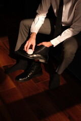 Fototapeta premium portrait of a man in a suit cleaning black leather shoes