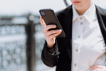 A girl uses a mobile phone while walking on the street in spring. The concept of working on the Internet.