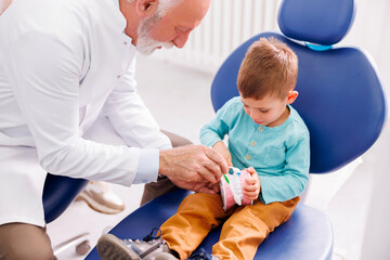 Dentist demonstrating teeth brushing to a little boy
