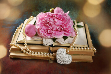 Vintage style arrangement with old books and pink peony on grunge background