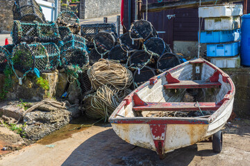 Row boat and lobster pots at a small boatyard at Peveril Point, on the shore or Swanage Bay -...