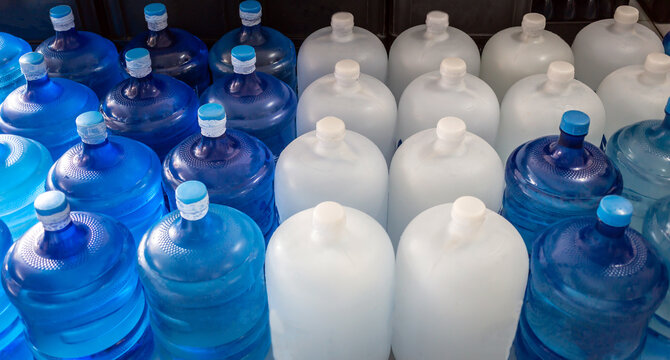 Top view of Plastic big bottles or white and blue gallons of purified drinking water inside the production line to prepare for sale. Water drink factory, small business