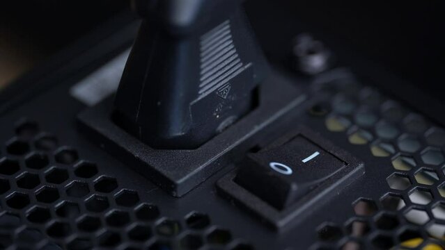 Close-up of a person pressing the black button on a computer to turn off the system unit.