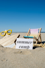 SUMMER CAMP text on paper greeting card on background of beach chair lounge starfish summer...