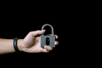 A hand is holding a fingerprint padlock. Isolated black background. Suitable for advertisement.