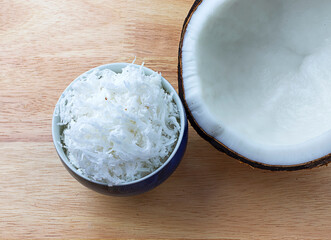 Coconut flakes Grated coconut in a cup with fresh coconut on a wooden floor