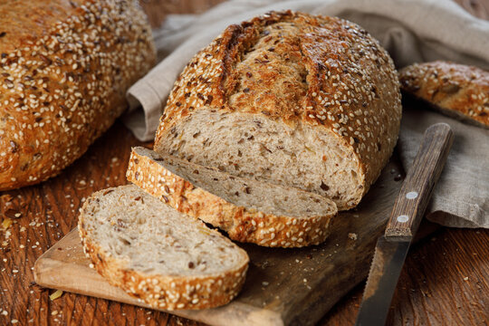 Rustic whole grain bread on a cutting board on a wooden kitchen table