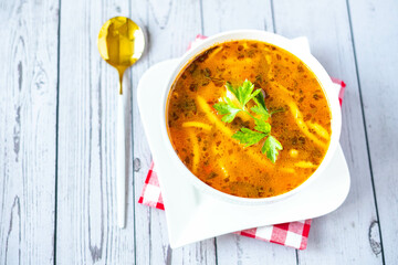 Homemade vegetables soup with borsch and parsley, in a white ceramic pot, on a white background. Vegetarian food, eating healthy. Eastern European cuisine