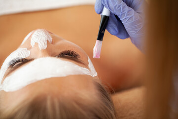 Young beautiful girl receiving facial mask in spa beauty salon