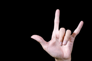 A hand is posing a metal gesture. Isolated black background.
