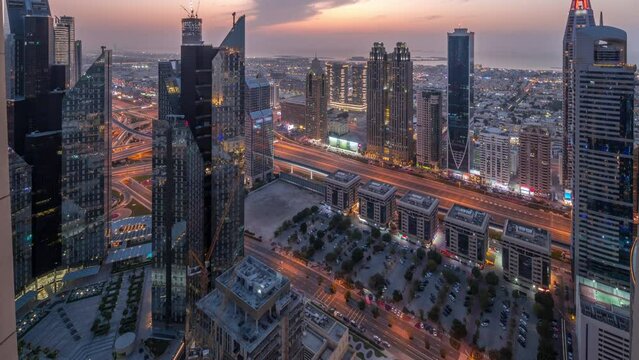 High-rise buildings on Sheikh Zayed Road in Dubai aerial day to night transition panoramic timelapse, UAE. Skyscrapers in financial district from above. City walk houses and villas on a background