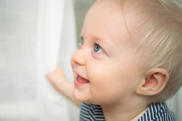 Cute baby with blue eyes - closeup portrait. Little boy at home looking away.