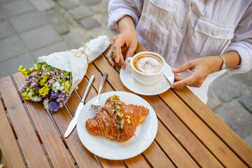 French breakfast made of a croissant and a cup of coffee on the summer terrace in the cafe