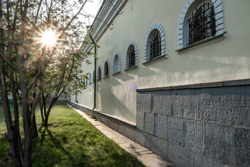 The long stone wall of the house with arched windows.