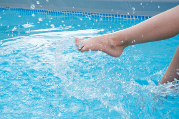 Kids legs splashing in water near swimming pool outdoors. Summertime activities for children. Copy...